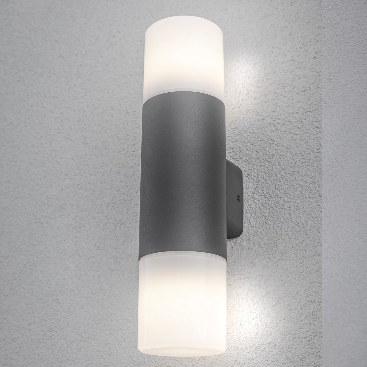 Our Cortez wall light looks great in modern settings. This wall light has a modern tube design with anthracite finish aluminium body and 2 polycarbonate opal diffusers. This wall light is perfect for any outdoor space requiring light and security such as gardens, driveways, doorways workspaces, pubs and hotels.